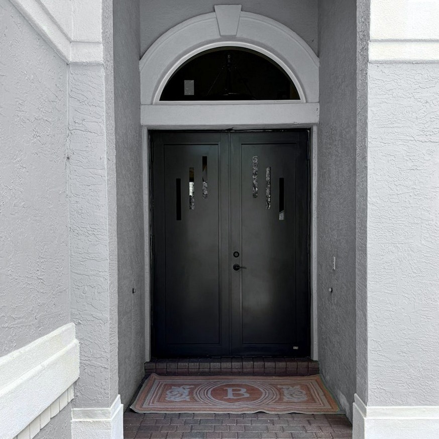 Black impact double entry doors with arched transom on a modern gray home